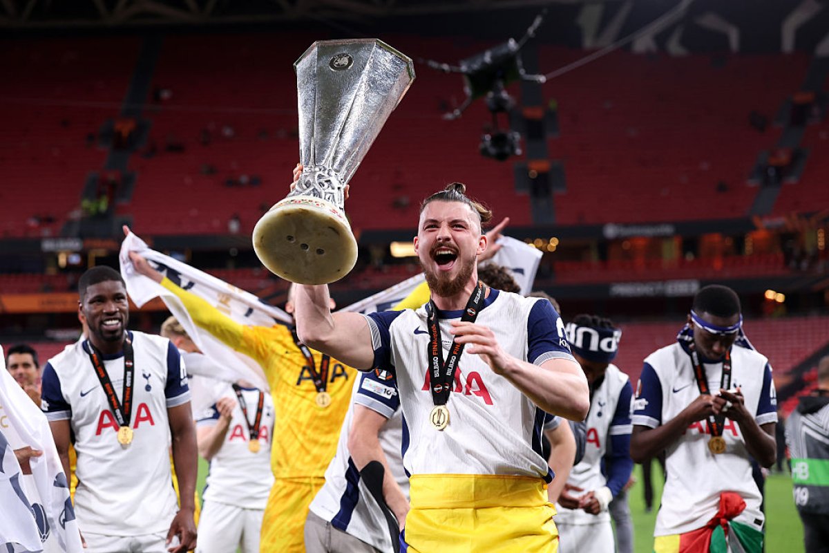 Radu Drăgușin cu trofeul UEFA Europa League în mână și drapelul României la brâu